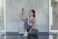 Young asian attractive smiling active fitness sitting on the floor of the gym and taking a selfie