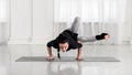 Young asian attractive woman practicing yoga, standing in Dragonfly pose. Sport in white hall.