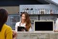 Young asian barista taking note, order, at coffee cafe counter w