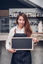 Young asian barista wear jean apron holding blank blackboard coffee menu at counter bar with smile face,cafe service concept, Royalty Free Stock Photo