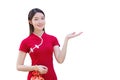 Young Asian beautiful confident woman in red dress stands holding red bag is pointing hand to present something while isolated on Royalty Free Stock Photo