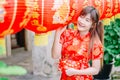 Young asian beautiful girl in chinese traditional red dress smile stand near china lamp, in the Chinese New Year. Festivities. Royalty Free Stock Photo