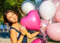 Young asian beautiful woman with flying multicolored balloons in the city. Royalty Free Stock Photo