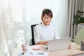 Young Asian beautiful woman works for a computer from a home with a laptop at desk as a freelancer Royalty Free Stock Photo