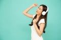 Young Asian beauty woman dancing and listening music with headphones on smartphone on green background.
