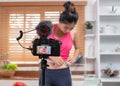 Young Asian blogge holding measuring tape around her wais while recording video on camera at home.media influencer reviewing and