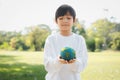 Young asian boy holding planet Earth globe at natural park background. Gyre Royalty Free Stock Photo