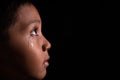 Young asian boy looking into light in darkness with tears in his eye