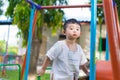 Young Asian boy play a iron train swinging at the playground under the sunlight in summer. Royalty Free Stock Photo