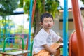 Young Asian boy play a iron train swinging at the playground under the sunlight in summer. Royalty Free Stock Photo