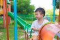 Young Asian boy play a iron train swinging at the playground under the sunlight in summer. Royalty Free Stock Photo