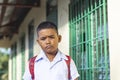 A young asian boy pouting while outside the classroom. Facial reaction after being scolded or grounded. A rural elementary student