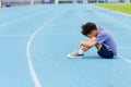 Young Asian boy sit on blue track in the stadium Royalty Free Stock Photo