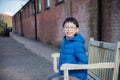 Young asian boy sits on vintage wood chair and brick Royalty Free Stock Photo