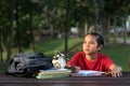 Young asian boy studying at park while looking at empty space