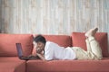 Young asian boy using laptop computer lying on a sofa at home. Royalty Free Stock Photo