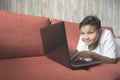 Young asian boy using laptop computer on a sofa at home. Royalty Free Stock Photo