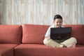 Young asian boy using laptop computer on a sofa at home. Royalty Free Stock Photo