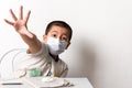 Young Asian boy wearing a face mask putting his hand out as if signalling to say stay away / keep your distance - a Social Royalty Free Stock Photo