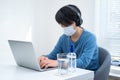 Young Asian boy wearing face mask working on laptop Royalty Free Stock Photo