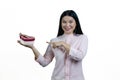 Young asian brunette woman is pointing at heart-shaped gift box on her palm. Royalty Free Stock Photo