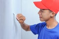 Young Asian builder man applying putty plaster on the white wall