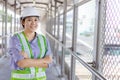 Young asian business engineer or technician inspector woman in safety helmet standing arms crossed at construction work site