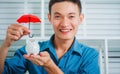 Young asian business man holding umbrella for protection piggy bank for property investment concept Royalty Free Stock Photo