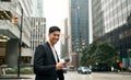 Young Asian business man professional standing in city using phone. Vertical Royalty Free Stock Photo