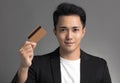 Young asian business man showing credit card isolated over gray background Royalty Free Stock Photo