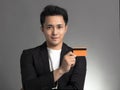 Young asian business man showing credit card isolated over gray background Royalty Free Stock Photo