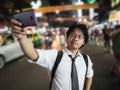 Young Asian business man taking a picture or selfie in the street at night. Social and internet of thing concept Royalty Free Stock Photo