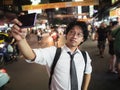 Young Asian business man taking a picture or selfie in the street at night. Social and internet of thing concept Royalty Free Stock Photo