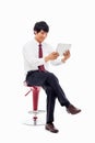 Young Asian business man using a pad PC sitting on the chair. Royalty Free Stock Photo