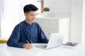 Young asian business man writing on notebook for planning working and using laptop computer on desk at home. Royalty Free Stock Photo