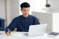 Young asian business man writing on notebook for planning working and using laptop computer on desk. Royalty Free Stock Photo