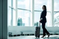 Young asian business woman in airport with baggage trolley bag, waiting for departure