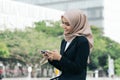 Young asian business woman on black suit sitting outside, using mobile phone Royalty Free Stock Photo