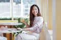 Young Asian business woman in casual clothes smile and sitting in cafe holding a glass of juice and looking out the window Royalty Free Stock Photo