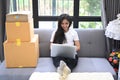 Young Asian business woman owner of SME online using laptop receive order from customer while sitting on sofa at her home. Royalty Free Stock Photo