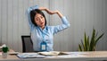 Young Asian Business woman sitting on the chair stretching herself and exercise for relaxation while working hard at office Royalty Free Stock Photo