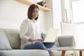 Young asian business woman sitting on couch at home working using laptop computer Royalty Free Stock Photo