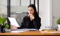 Young asian business woman sitting at her workplace and reading financial document Royalty Free Stock Photo