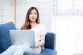 Young asian business woman smile and work from home with laptop computer online to internet on sofa in living room. Royalty Free Stock Photo