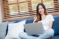 Young asian business woman smile and work from home with laptop computer online to internet on sofa. Royalty Free Stock Photo