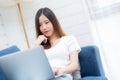 Young asian business woman smile and work from home with laptop computer online to internet on sofa in living room. Royalty Free Stock Photo