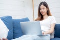 Young asian business woman smile and work from home with laptop computer online to internet on sofa in living room. Royalty Free Stock Photo