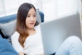 Young asian business woman smile and work from home with laptop computer online to internet on sofa in living room. Royalty Free Stock Photo