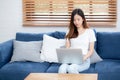 Young asian business woman smile and work from home with laptop computer online to internet on sofa. Royalty Free Stock Photo