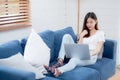 Young asian business woman smile and work from home with laptop computer online to internet on sofa. Royalty Free Stock Photo